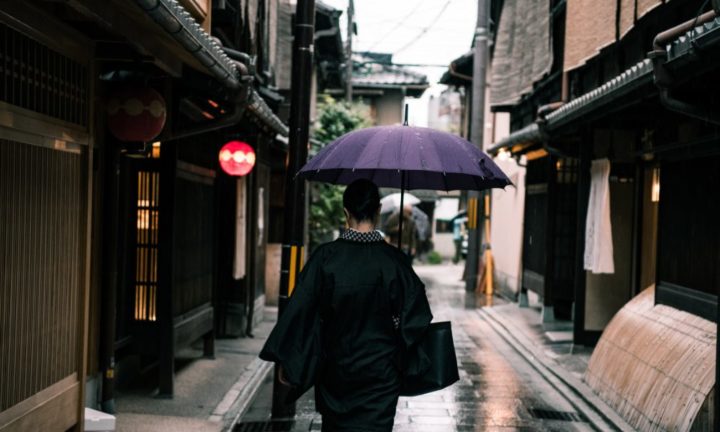 a woman walking in kyoto japan with an umbrella