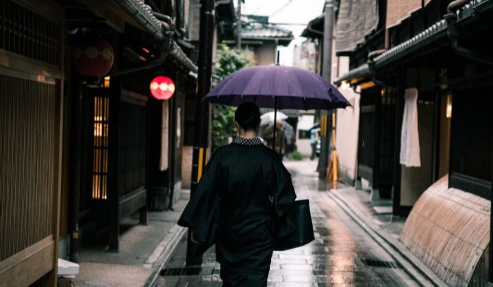 a woman walking in kyoto with an umbrella