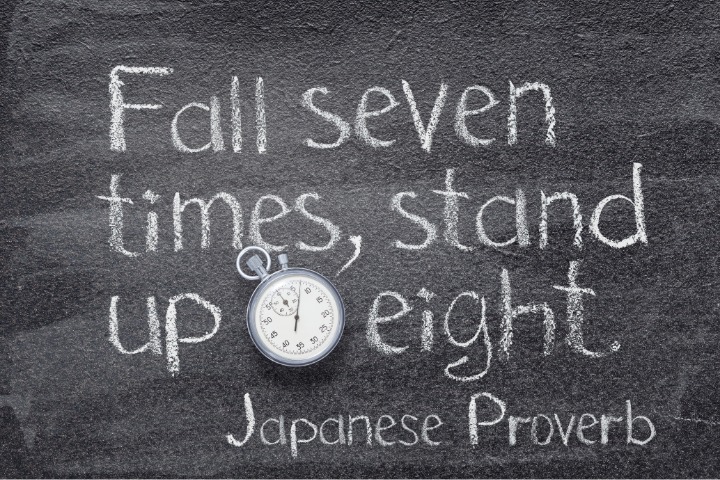 Fall seven times stand up eight phrase written by chalk with a clock: example of popular Japanese proverbs