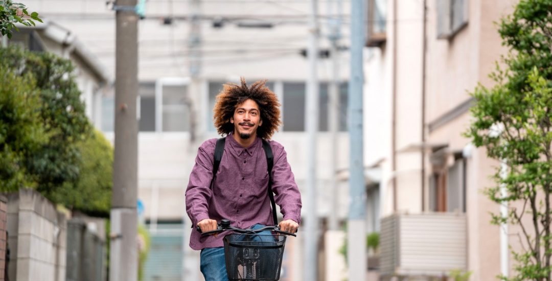 photo of a man on a bike cycling down a street in japan