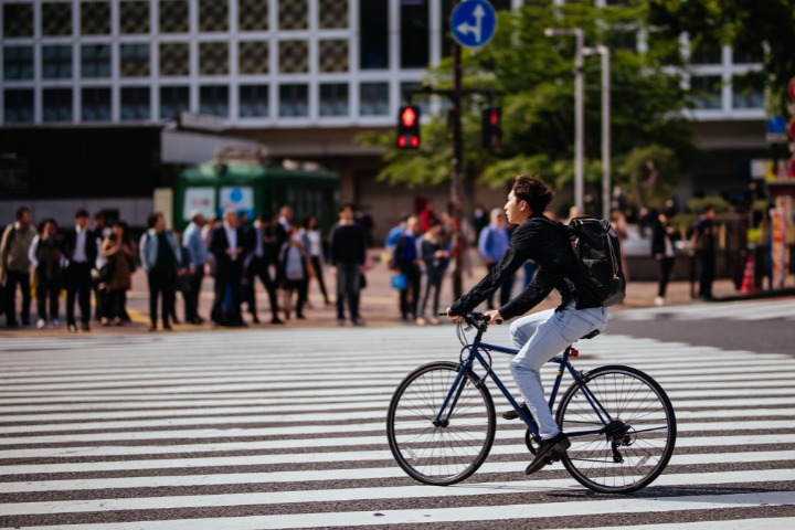 man cycling across a crossing in Japan