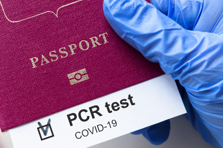 PCR test certificate kept within red passport to enter the borders