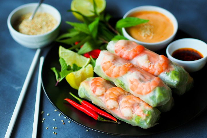 some vietnamese spring rolls beautifully presented on a plate with seasonings