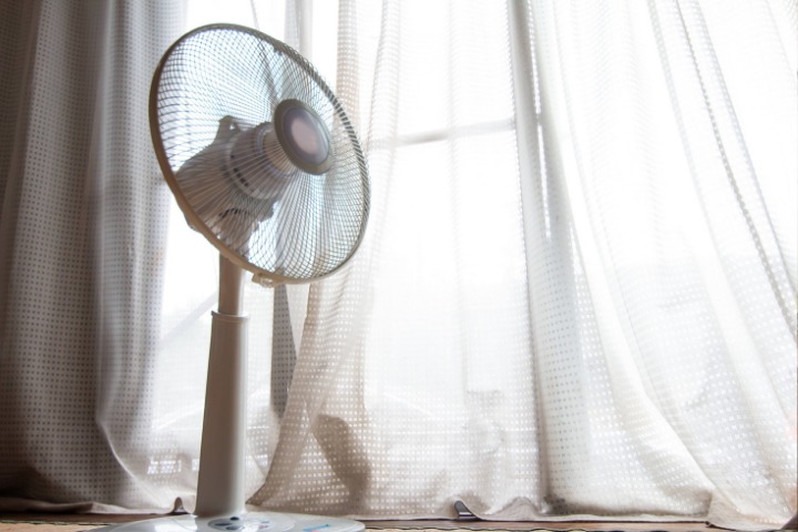 A fan in the house with white curtains