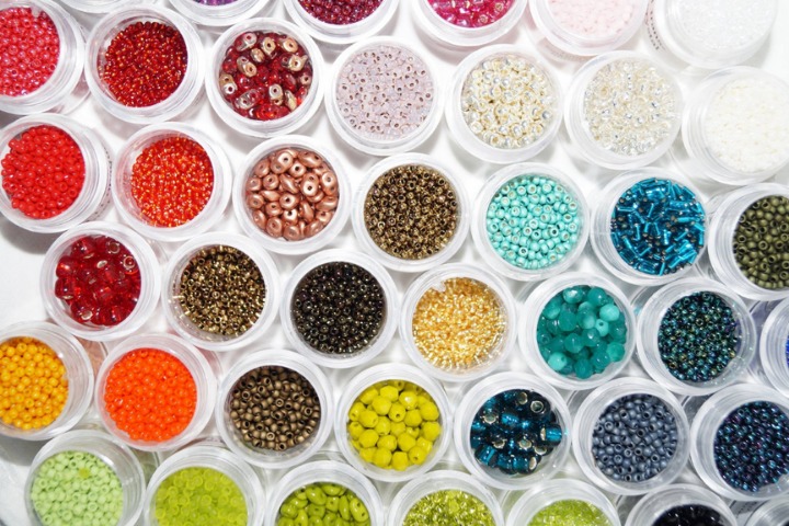 a photo of seed beads in many different colours in small pots for jewelry making 
