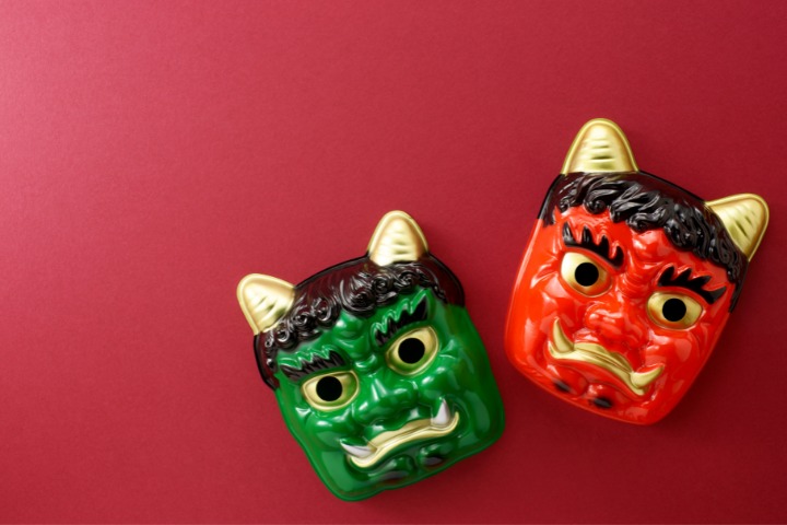 a photo of two plastic japanese demon masks on a red background