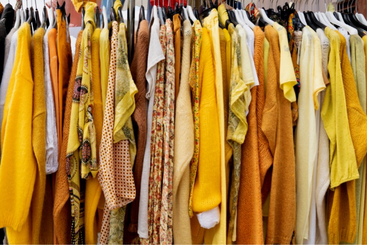 photo of yellow secondhand clothing on a clothes rack in a thrift shop
