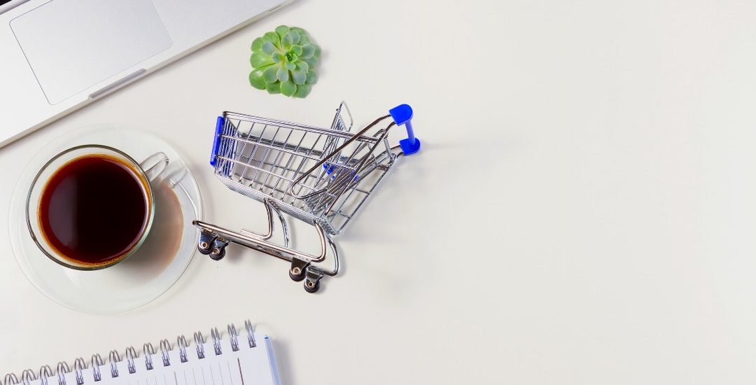 a photo of a small trolley, plant, notebook, coffee and laptop representign online shopping in japan