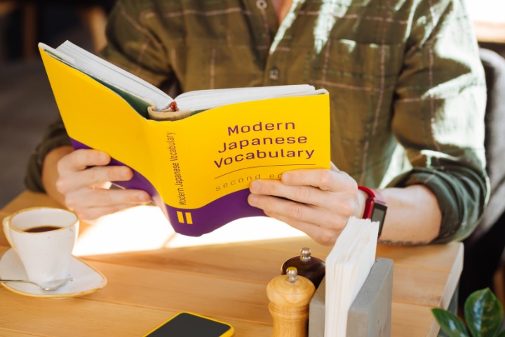 A man is reading a modern Japanese Vocabulary book. 