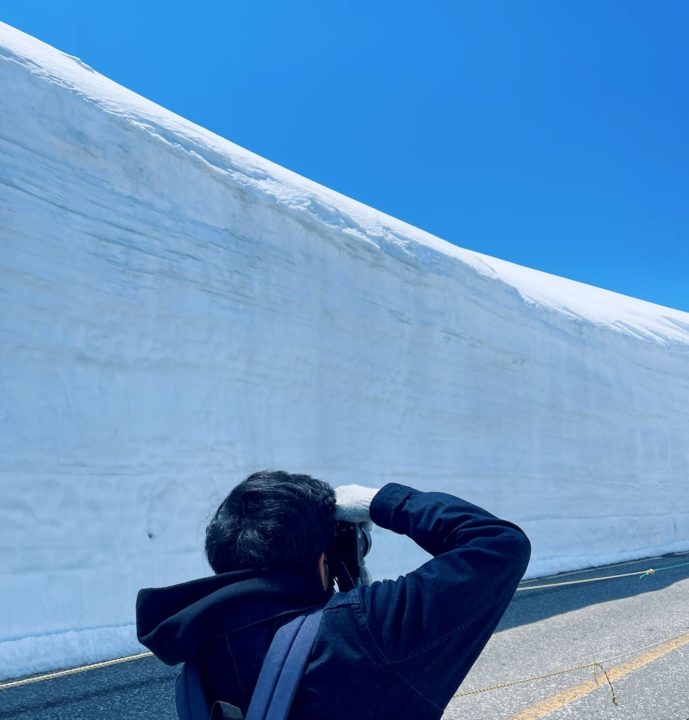 a photo of a man taking a photo of the tateyama alpine route murodo snow wall