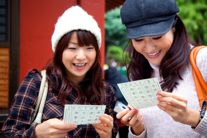 a photo of two girls reading their omikuji fortunes