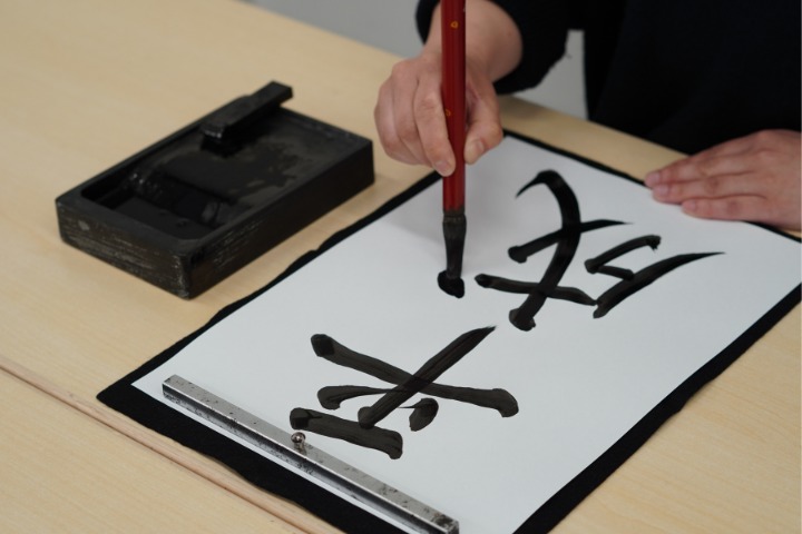 a photo of someone doing japanese calligraphy writing the word heisei