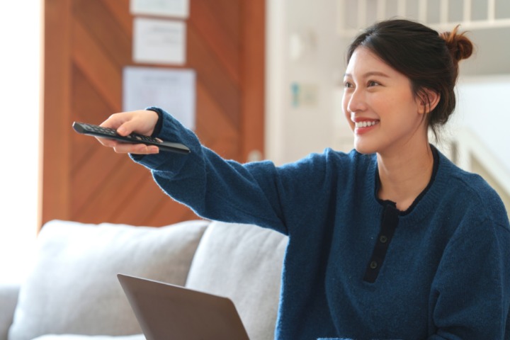 a photo of a woman holding a tv remote up and smiling