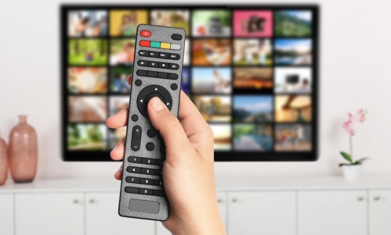 a photo of a hand holding a remote in front of a television