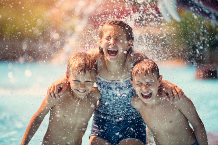 Three people smiling in a water park