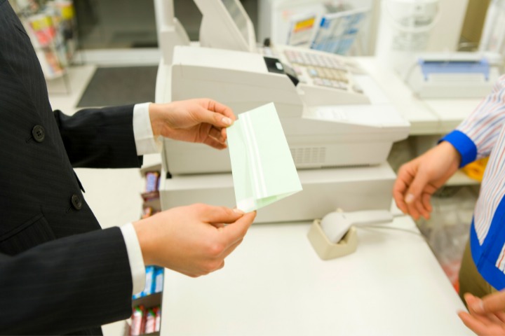 a photo of someone handing over an envelope at a konbini convenience store register in japan