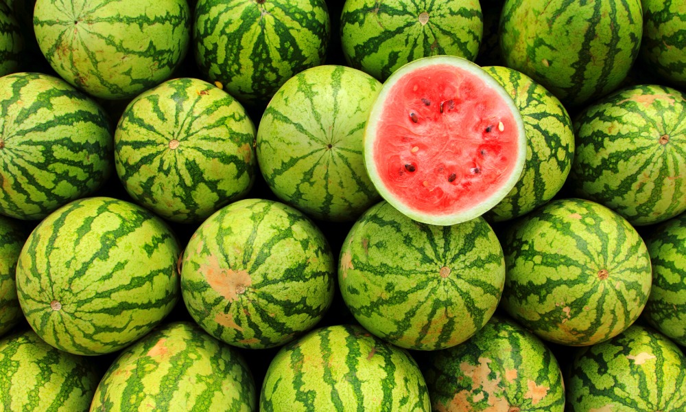 a photo of a half cut watermelon on a bed of watermelons