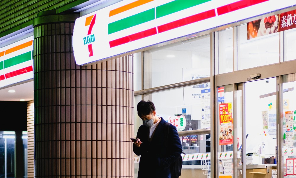 a photo of a man standing out side of a japanese konbini convenience store at night