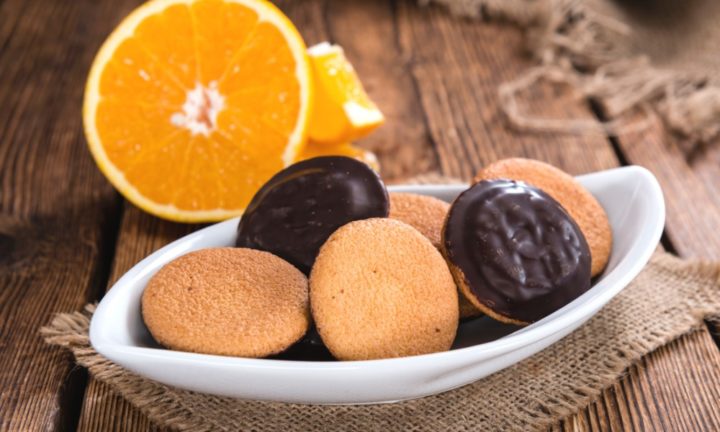 a photo of jaffa cakes on a wooden table with orange in background