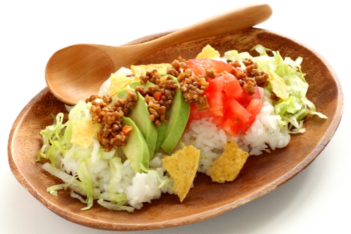 a photo of okinawan cuisine taco rice in a wooden bowl with wooden spoon