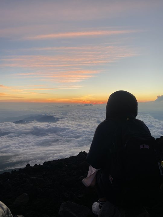 Hiker is sitting on Fuji san watching the sunset