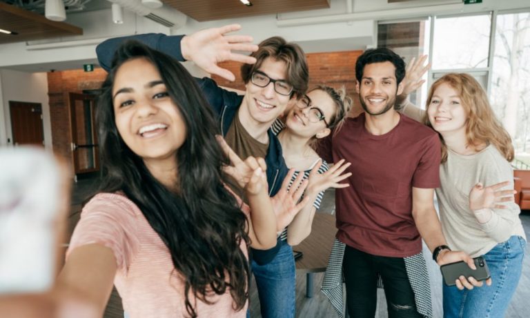 A group of international students from diverse backgrounds pose for a selfie.
