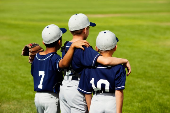 A group of kids standing together on a field, wearing Japanese baseball gear, ready for their game.