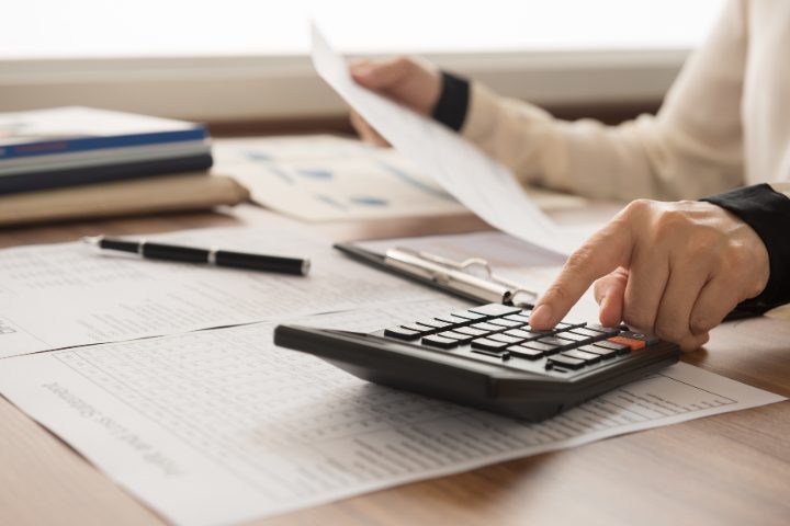 Person using a calculator while reviewing documents to plan expenses